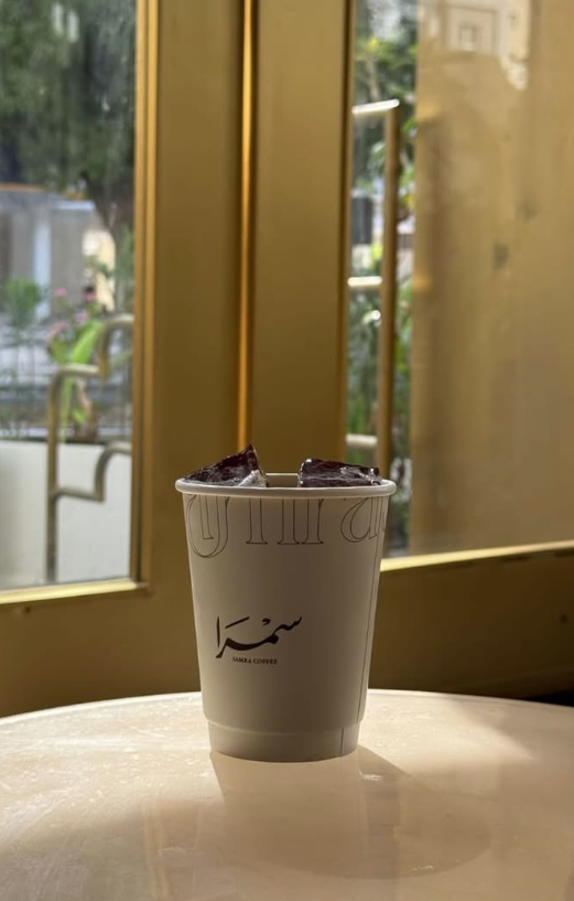 Iced coffee cup on marble by a brass window