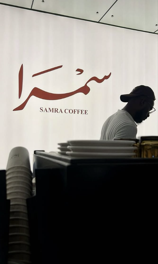 Barista at work beneath the Samra Coffee logo wall